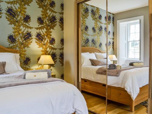 a bedroom with two beds and a mirror at Riverside Cottage in Blair Atholl