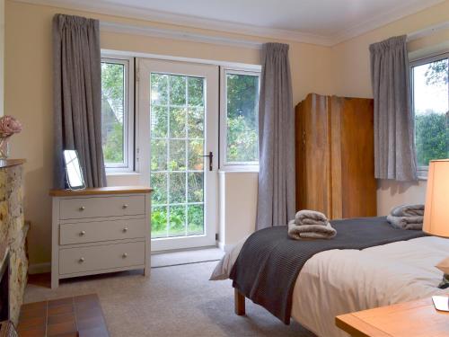 a bedroom with a bed and two windows at The Mill Cottage in Ault Hucknall