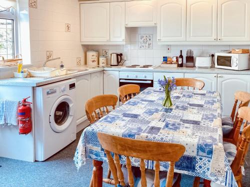 a kitchen with a table with chairs and a washing machine at The Haven in Crantock