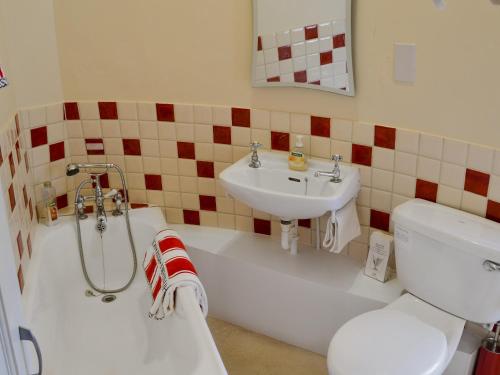 a bathroom with a sink and a toilet and a bath tub at The Mill The Mill House in Ludham