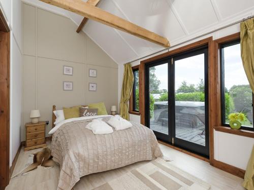 a bedroom with a bed and a large window at Toad Hall Cottage in Earls Colne