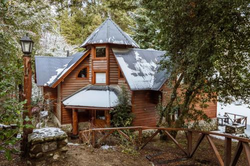 Una cabaña en el bosque con nieve en el techo. en BOG Torres del Bayo, en Villa La Angostura