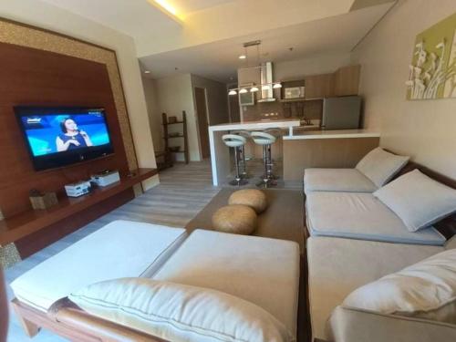 ein Wohnzimmer mit Sofas, einem TV und einer Küche in der Unterkunft Luxurious Family Room Pico de Loro in Nasugbu