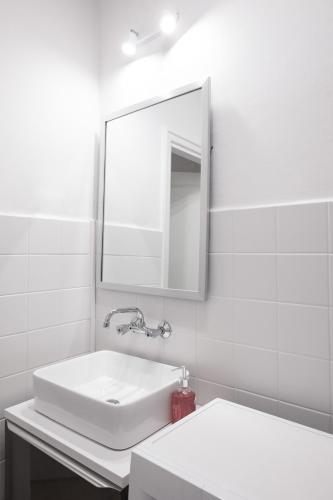 a white bathroom with a sink and a mirror at ClickTheFlat Wilcza 35 City Center Apart Rooms in Warsaw