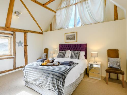 a bedroom with a large bed with a purple headboard at Laurel Barn in Ashwellthorpe