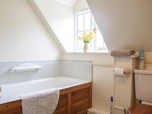 baño con bañera y ventana en Holly Cottage en Lilleshall