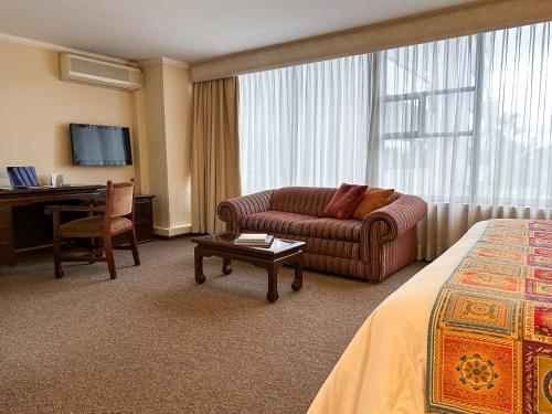 キトにあるLa Quinta by Wyndham Quitoのソファとデスクが備わるホテルルームです。