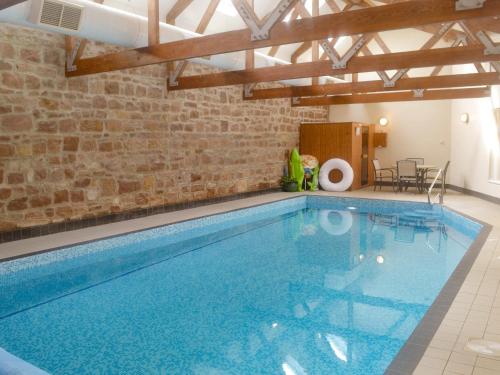 a large swimming pool with a brick wall at The Mill House in Warenford