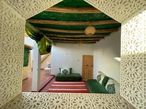 sala de estar con sofá verde y techo en Riad Mama Toutou, en Marrakech