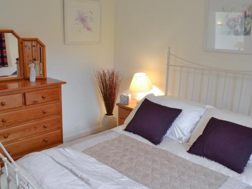 a bedroom with a bed and a dresser at Moonrakers in Ruan Lanihorne