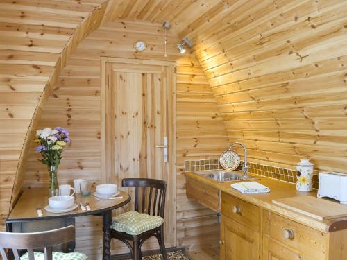 una cocina con mesa y fregadero en una cabaña de madera en The Squirrels strelley Barn en Woodham Mortimer