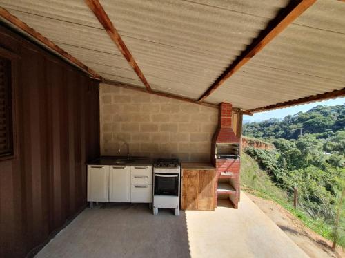 eine Außenküche mit einem Herd und einem Dach in der Unterkunft Casa Container na Serra da Bocaina in São José do Barreiro