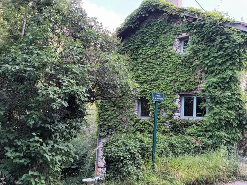 une maison recouverte de lierre avec un panneau devant elle dans l'établissement Deux pièces de caractère au cœur des gorges, à Engins