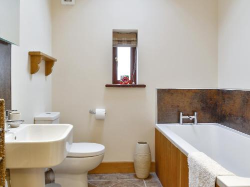 a bathroom with a tub and a toilet and a sink at The Old Byre in Dearham