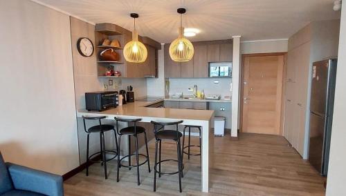 a kitchen with a counter and bar stools at TuArriendoCL-MPHB402 Dpto con vista al Lago 2D2B hasta 5Pax in Puerto Varas