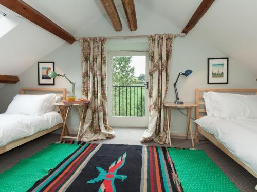 a bedroom with two beds and a balcony at Rhydleos Mill in Llansilin