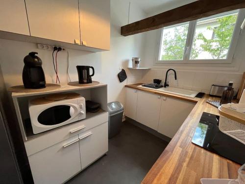 une petite cuisine avec un four micro-ondes sur un comptoir dans l'établissement « L’Hilo » Appart 4 Personnes À 250 m de la Plage, à Varaville