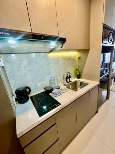 a small kitchen with a stove and a sink at Verdela Pollux Meisterstadt Batam apartement in Batam Center