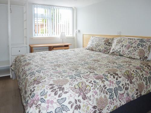 a bedroom with a bed with a floral bedspread and a window at Woodside in Burton