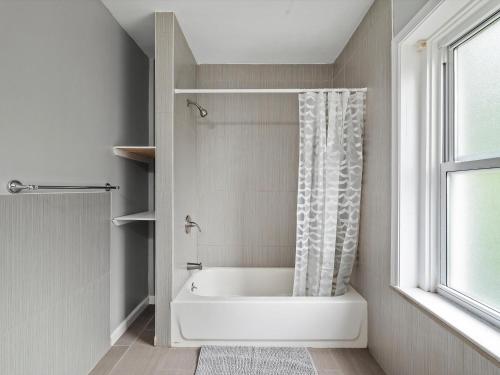 een witte badkamer met een bad en een raam bij Oakland/University @H Bright and Stylish Private Bedroom with Shared Bathroom in Pittsburgh