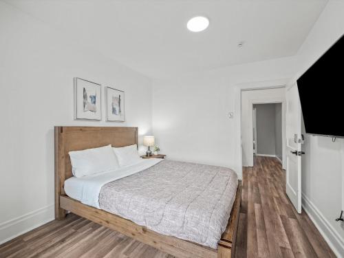 a bedroom with a large bed with white walls and wooden floors at Oakland/University @H Bright and Stylish Private Bedroom with Shared Bathroom in Pittsburgh