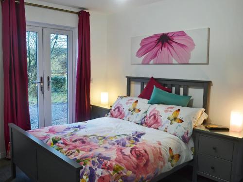 a bedroom with a bed and a window with red curtains at Stable Cottage in Stewarton