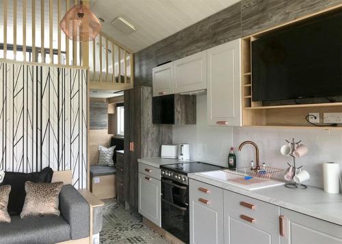 a kitchen with white cabinets and a couch in a room at Torvean Holiday Park in Inverness