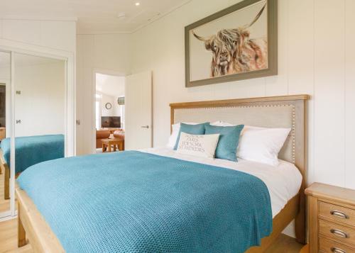a bedroom with a large bed with a blue blanket at Drumcarrow Luxury Lodges in St Andrews