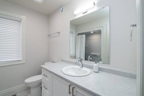 ein Badezimmer mit einem Waschbecken, einem WC und einem Spiegel in der Unterkunft Stylish House W a Media Room Near Downtown Picton in Picton