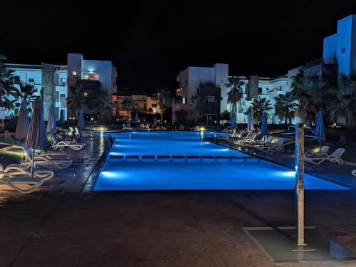 a large swimming pool with blue lights at night at Perla à 200 m de la plage in Saidia 