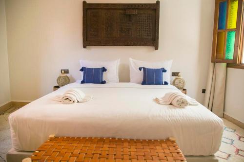 um quarto com uma grande cama branca com almofadas azuis em Riad Sabria em Marrakech
