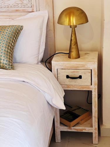 a bedside table with a lamp on it next to a bed at Riad Al Manara in Essaouira