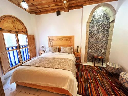 a bedroom with a large bed and a large window at Riad Al Manara in Essaouira