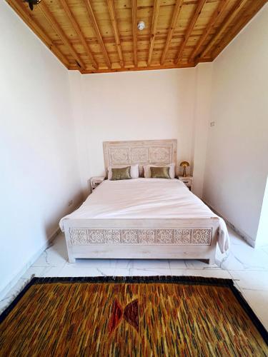 a white bed in a room with a wooden ceiling at Riad Al Manara in Essaouira
