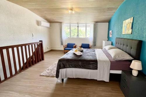 1 dormitorio con 1 cama grande y pared azul en HEIPOE LODGE - 6 min airport, Wifi, AC & Parking en Papeete