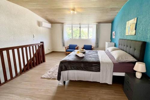 a bedroom with a large bed with a blue wall at HEIPOE LODGE - 6 min airport, Wifi, AC & Parking in Papeete