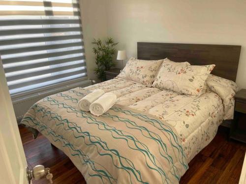 1 dormitorio con 1 cama con 2 toallas en Departamento manantiales, en Punta Arenas