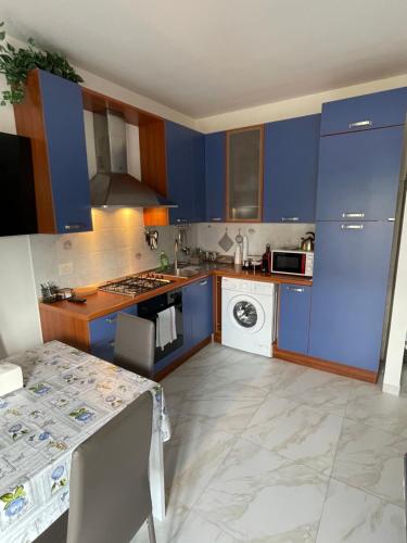 una cocina con armarios azules y una mesa. en Casa Iris, en Rozzano
