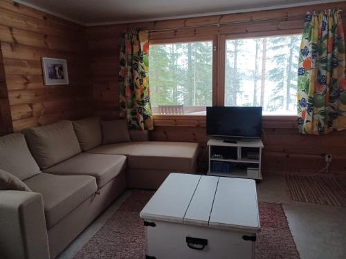 a living room with a couch and a tv at Jamali Cabin in Lieksa