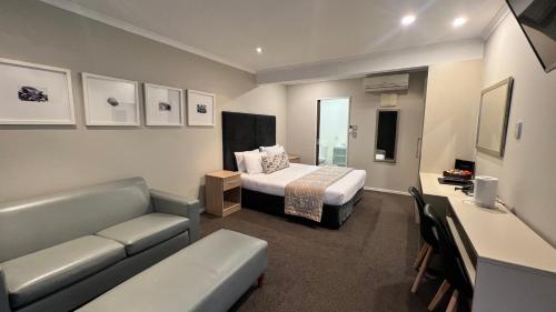 a bedroom with a bed and a couch in a room at Marineland Beachfront Accommodation in Napier