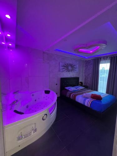 a purple room with a tub and a bed at Nid d'Amour in Strasbourg
