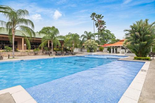 a swimming pool at a resort with palm trees at Copantl Hotel & Convention Center in San Pedro Sula