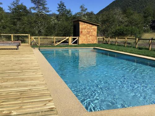 a swimming pool with a wooden deck next to a fence at Piedra Nevada in Malalcahuello
