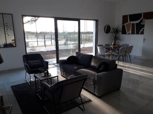 un salon avec un canapé, des chaises et une table dans l'établissement Maison neuve de standing 150 m2, à Croix-Chapeau