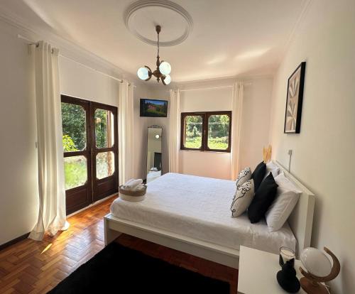 um quarto com uma grande cama branca e 2 janelas em VILA GUIA in Valdreu em Braga