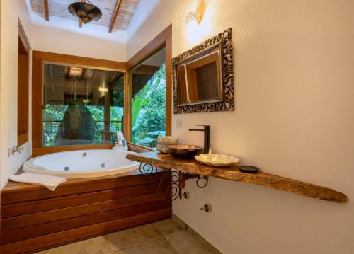 a bathroom with a tub and a large window at Hotel Vila Kebaya in Ilhabela