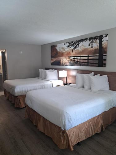two beds in a hotel room with a painting on the wall at Days Inn & Suites by Wyndham Rocky Mount Golden East in Rocky Mount