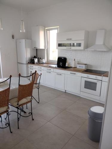 - une cuisine avec des appareils blancs, une table et des chaises dans l'établissement Tandem apartman, à Kápolnásnyék