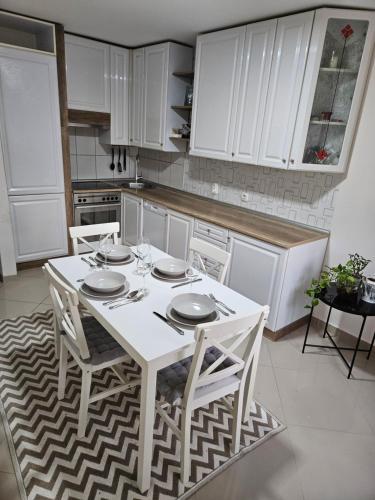 uma cozinha com uma mesa branca e armários brancos em Epicentar apartment em Loznica