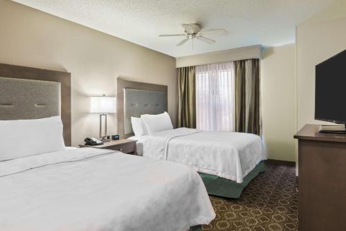 a hotel room with two beds and a flat screen tv at Homewood Suites by Hilton Baton Rouge in Baton Rouge